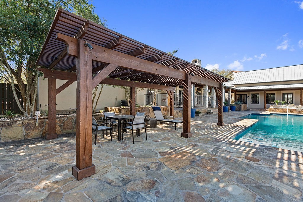 a patio with a pool and a wooden pergola
