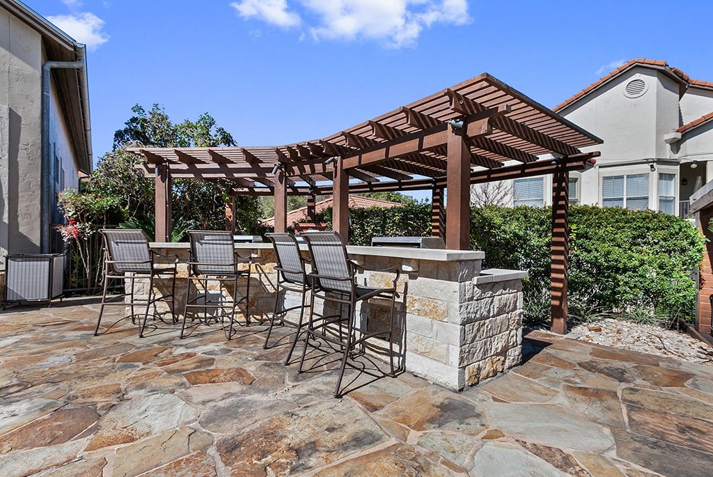 a stone patio with a bar and a pergola