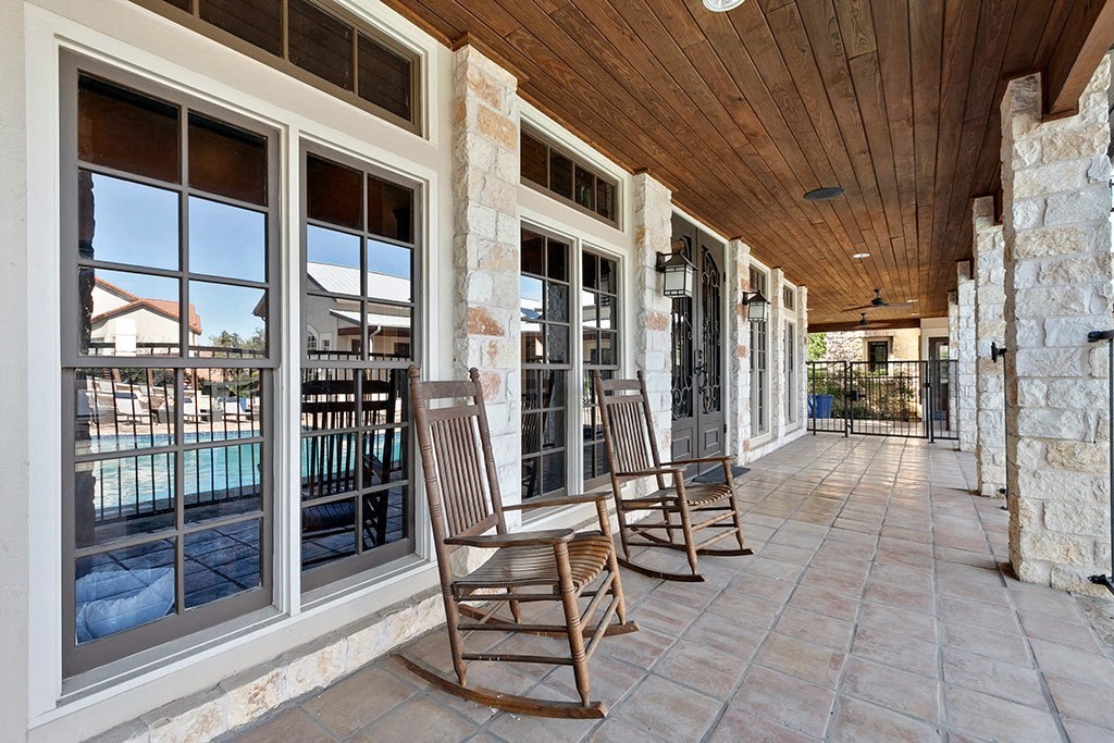 a covered porch with rocking chairs and a pool