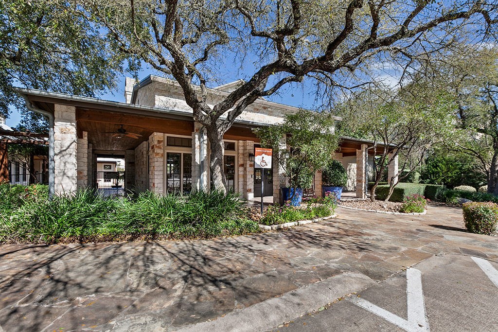 the front of a brick building with trees and plants