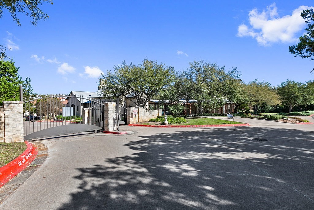 a street in a neighborhood with a fence and trees