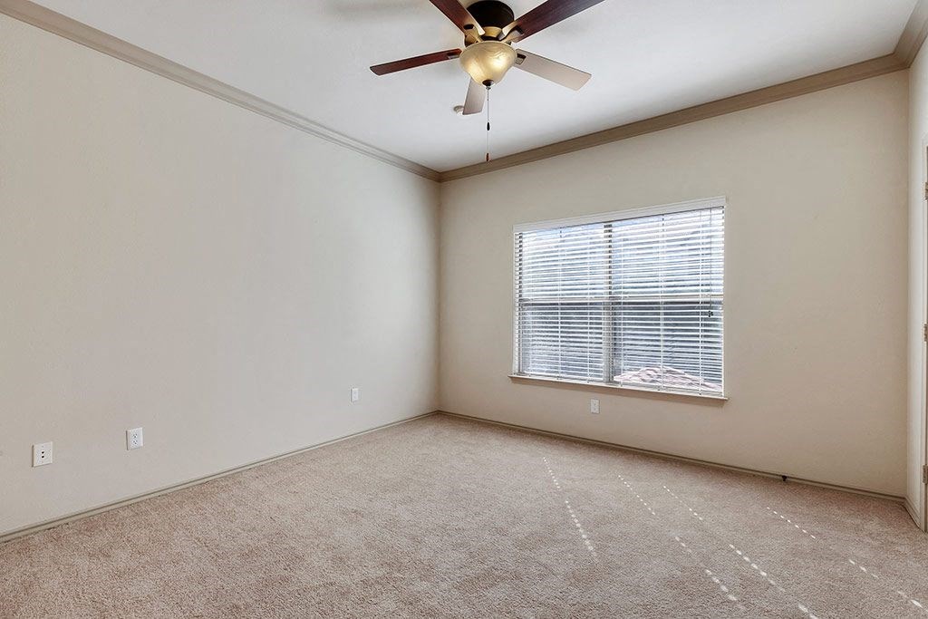 an empty living room with a ceiling fan and a window