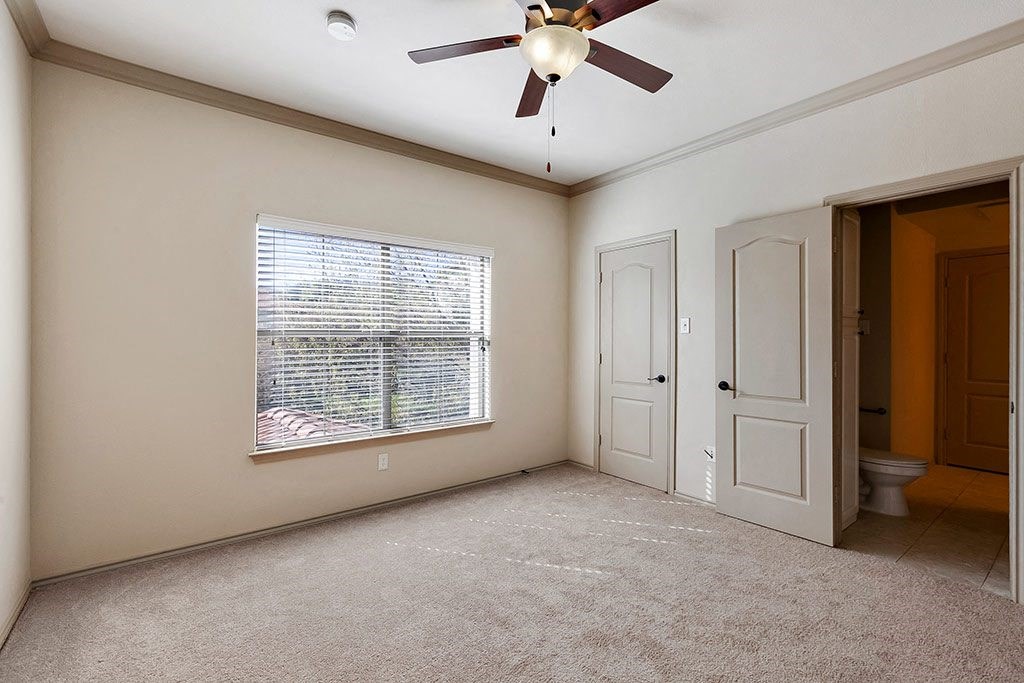 an empty living room with a ceiling fan and a window