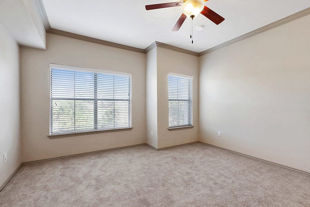 an empty living room with a ceiling fan and a window