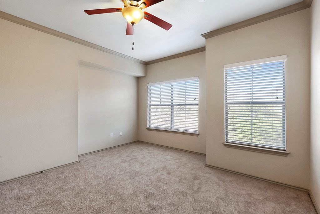 an empty living room with a ceiling fan and a window