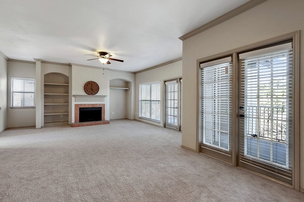 an empty living room with a fireplace and a ceiling fan