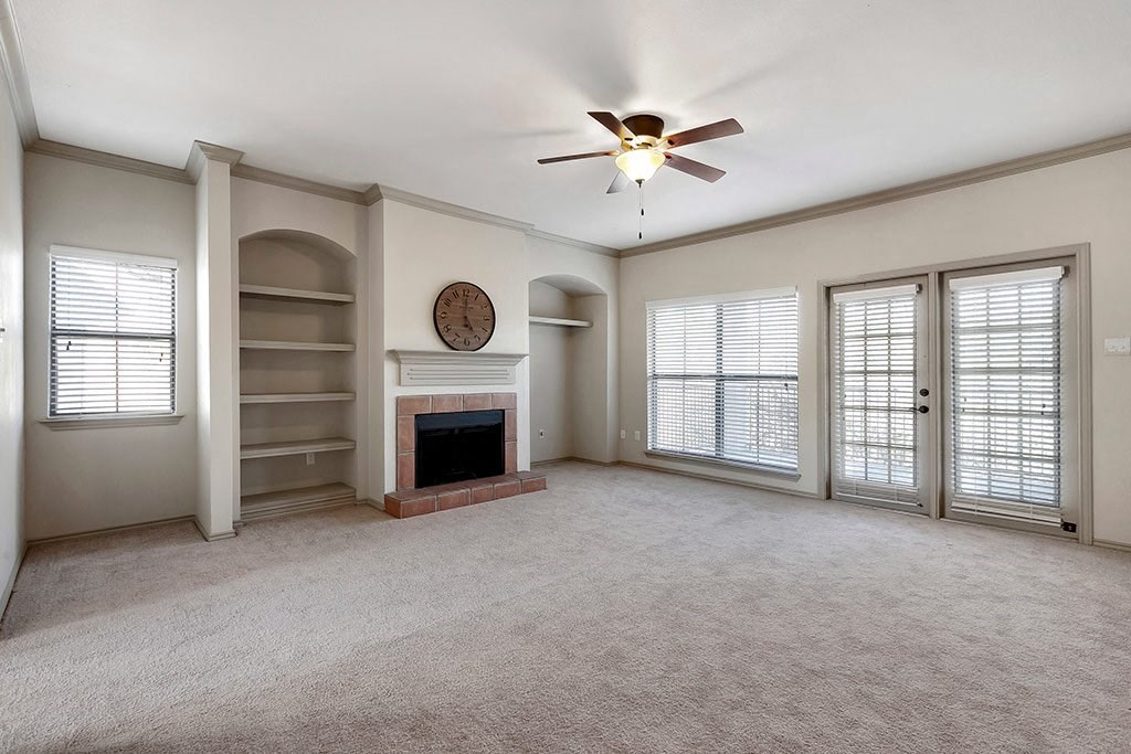 an empty living room with a fireplace and a ceiling fan