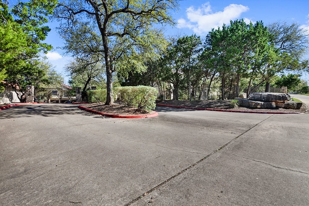 a parking lot with trees and shrubs and a car parked in it