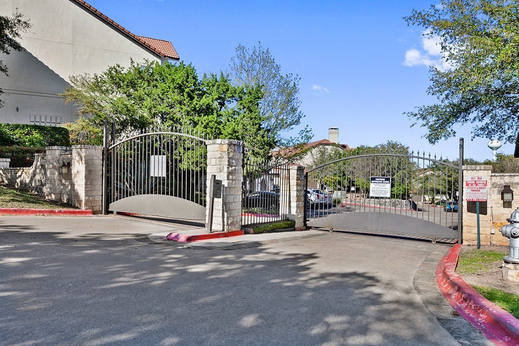 the gate of a church with a driveway and trees