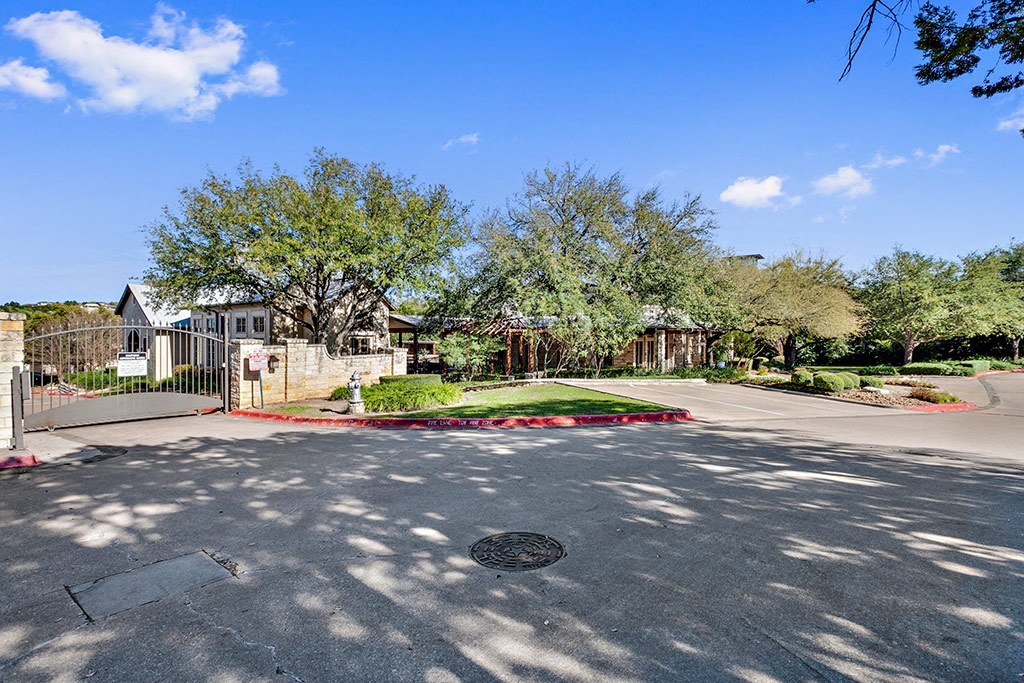 a parking lot with trees and a fence