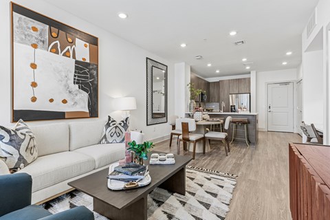 A modern living room with a large painting on the wall and a coffee table in the center.