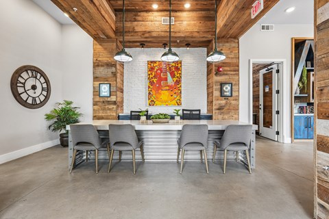 A dining room with a large table and grey chairs.