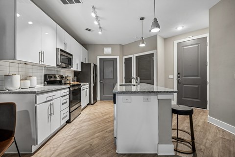 A modern kitchen with white cabinets and a wooden floor.