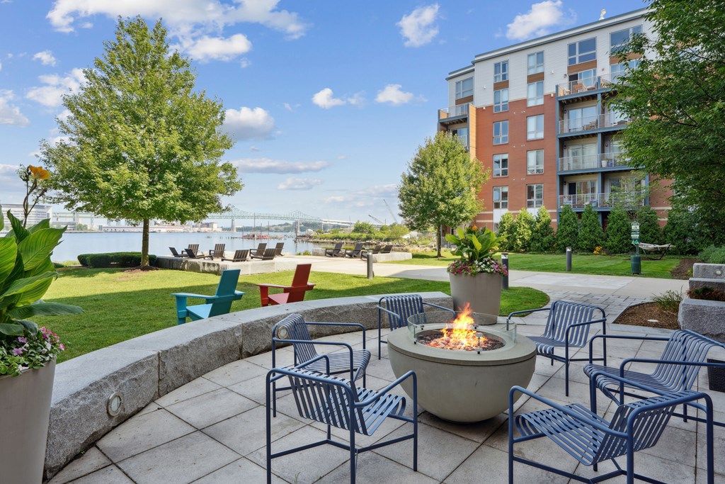 A fire pit sits in the middle of a patio surrounded by chairs.