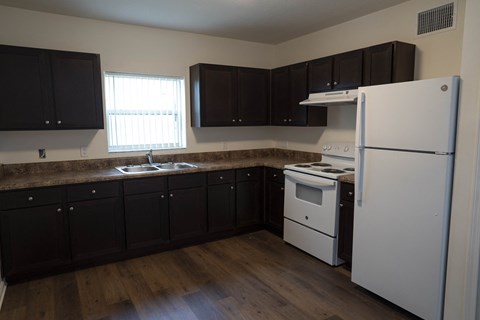 A kitchen with black cabinets and a white refrigerator.