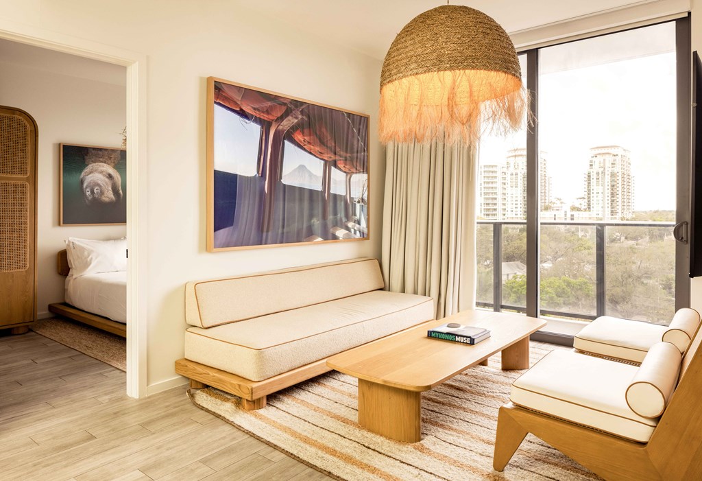 A living room with a large window and a painting on the wall.