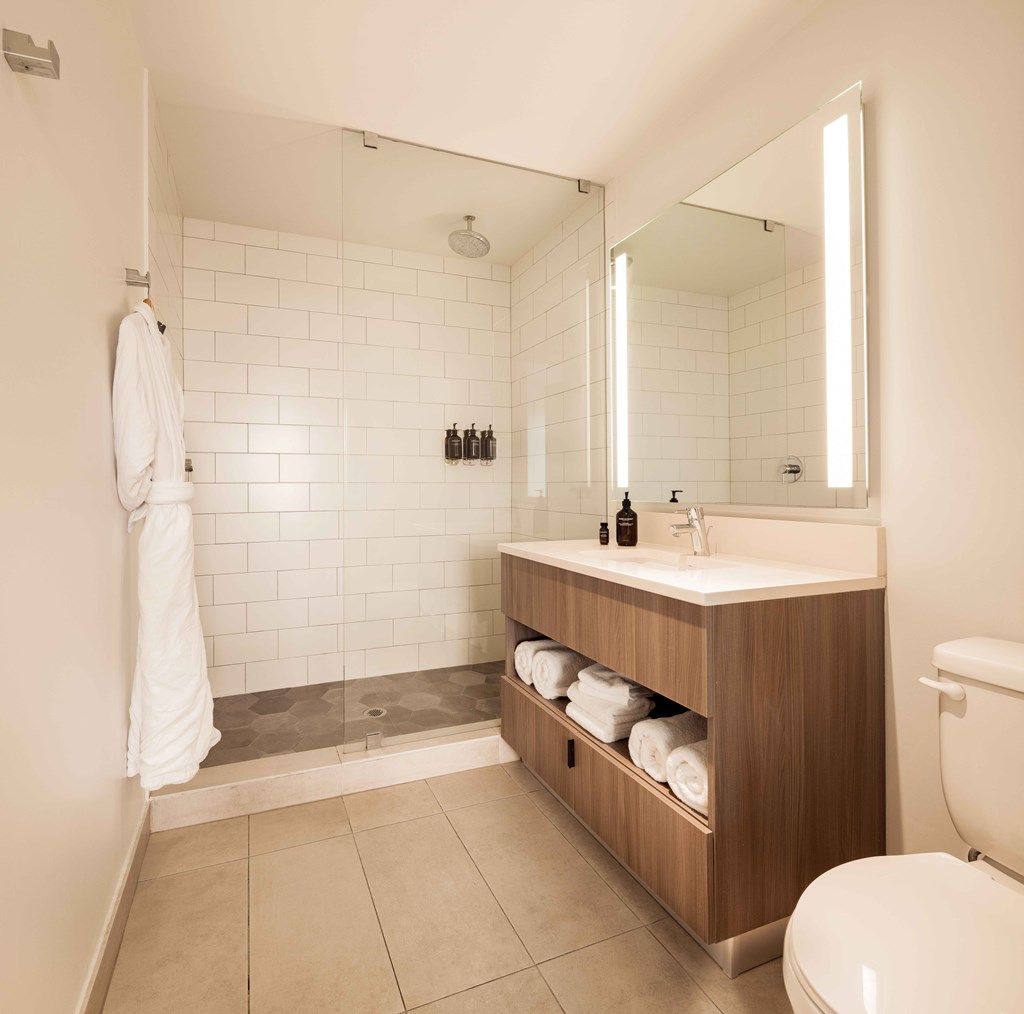 A white towel hangs on a white wall in a white bathroom.