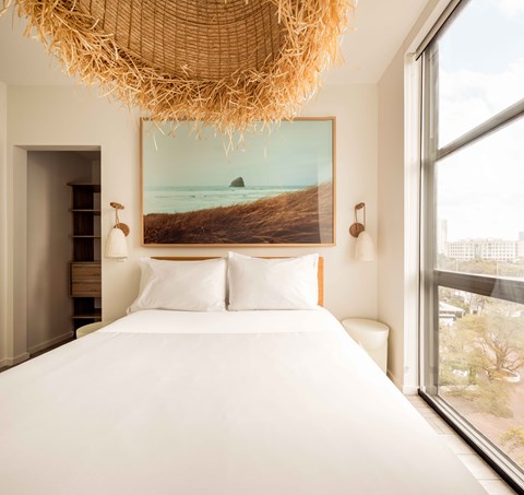 A bedroom with a large bed and a large painting of a beach scene on the wall.