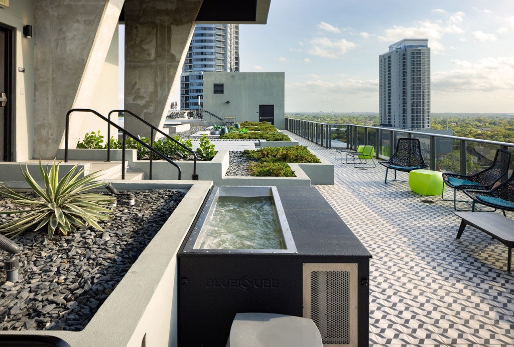 A modern outdoor patio with a hot tub and a view of the city.