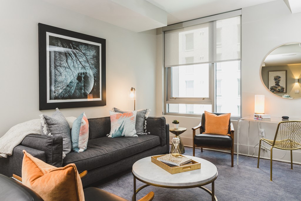 a living room with a black couch and orange chairs