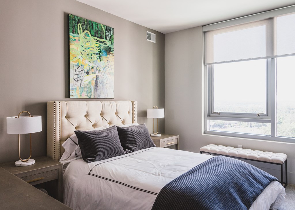 a bedroom with a large painting on the wall and a bed with a white tufted