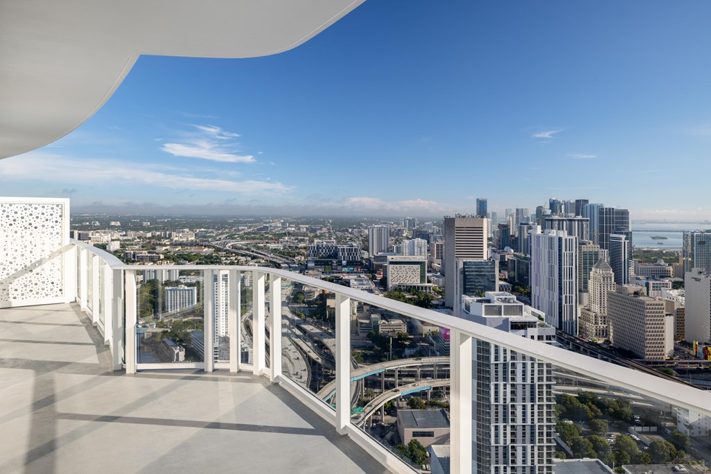 A white building with a balcony overlooking a cityscape.