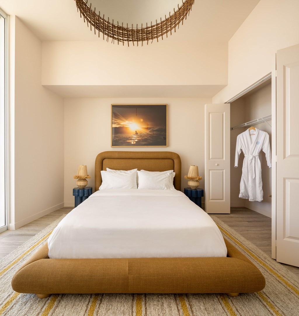 A bedroom with a large bed and a painting above it.