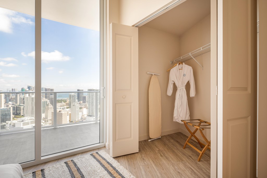 A white robe hanging on a rack in a room with a view of the city.