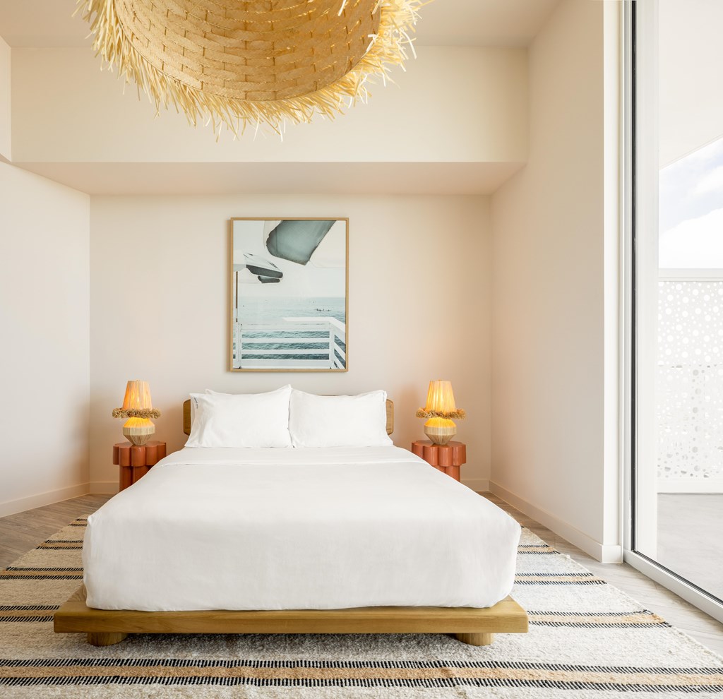 A bedroom with a large bed and a painting on the wall.