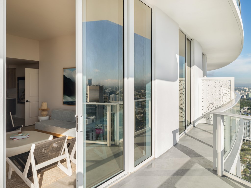 A modern balcony with glass doors overlooking a cityscape.