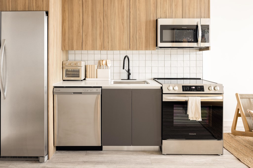 A modern kitchen with a refrigerator, oven, and microwave.