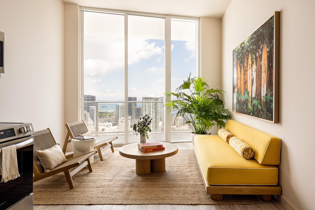 A living room with a yellow couch and a large window.