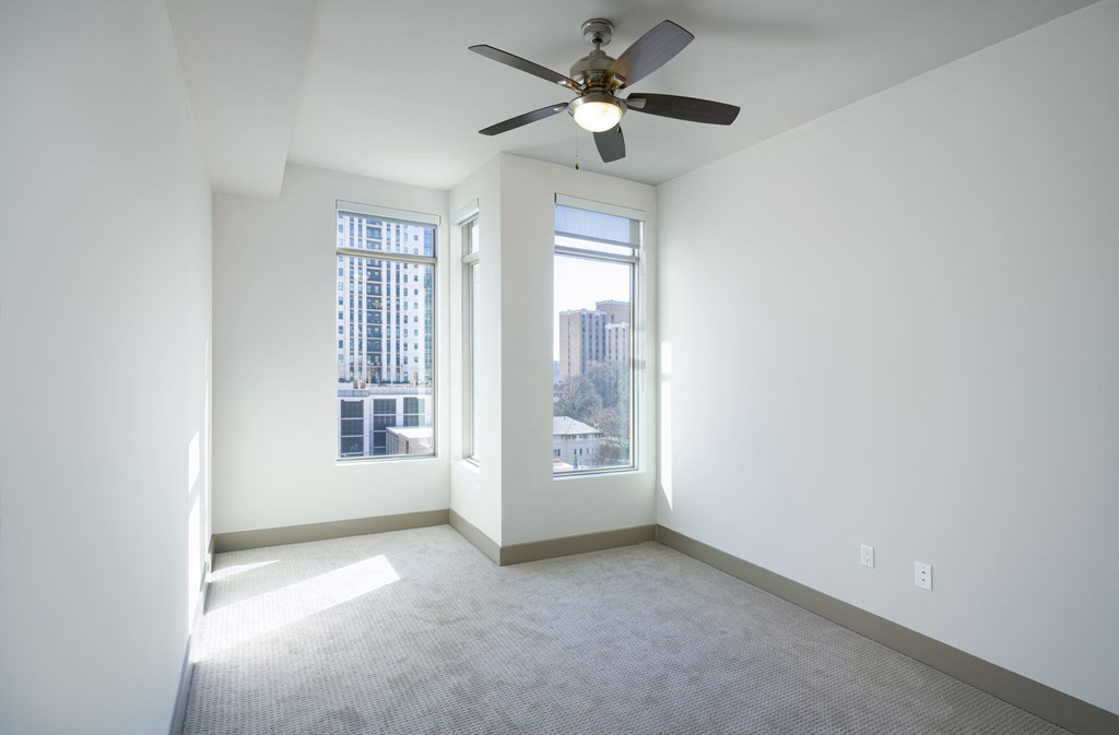 an empty living room with a ceiling fan and a window