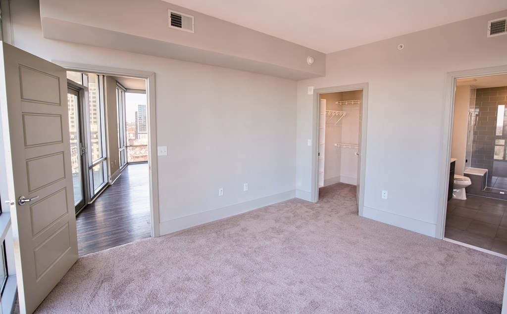 an empty living room with a door to a bedroom and a bathroom