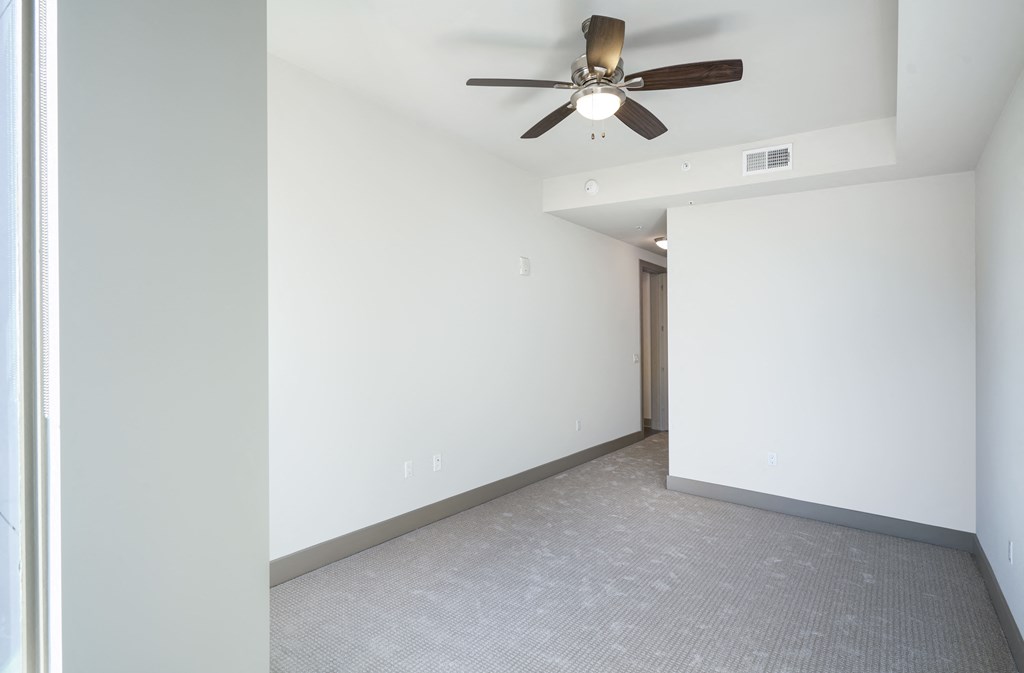 a living room with white walls and a ceiling fan
