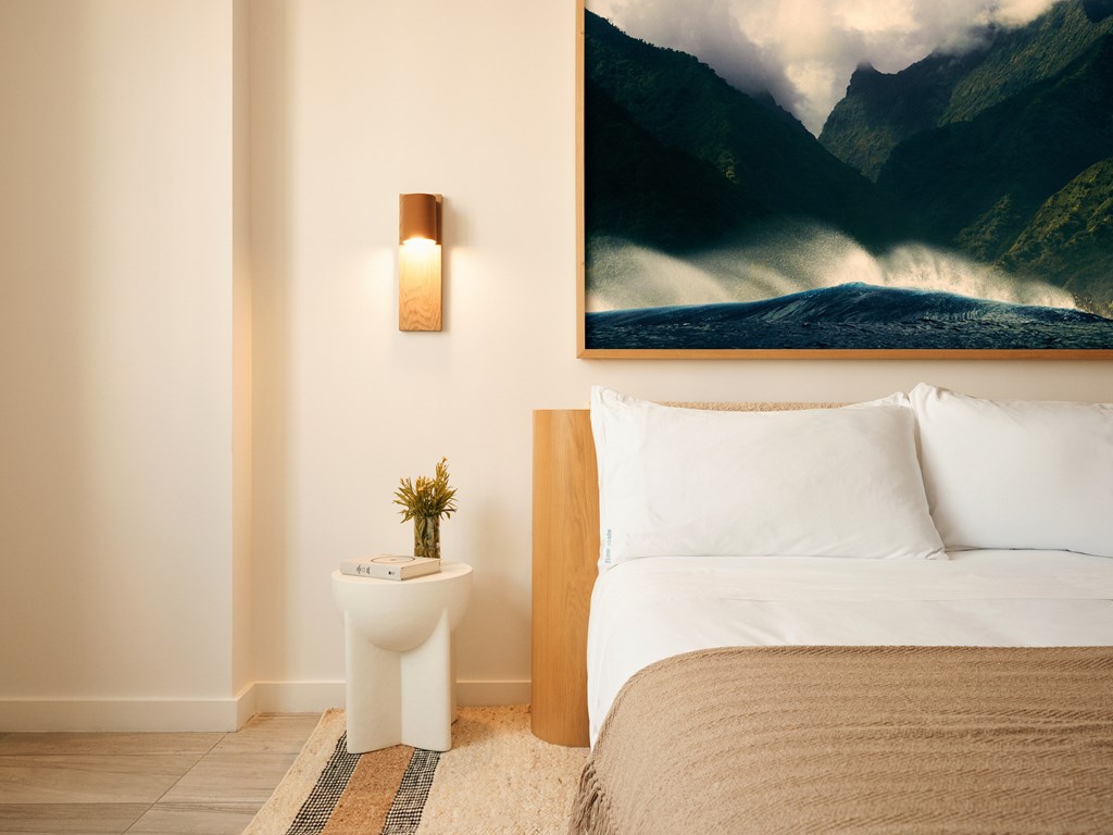 A bedroom with a large painting of a waterfall on the wall.
