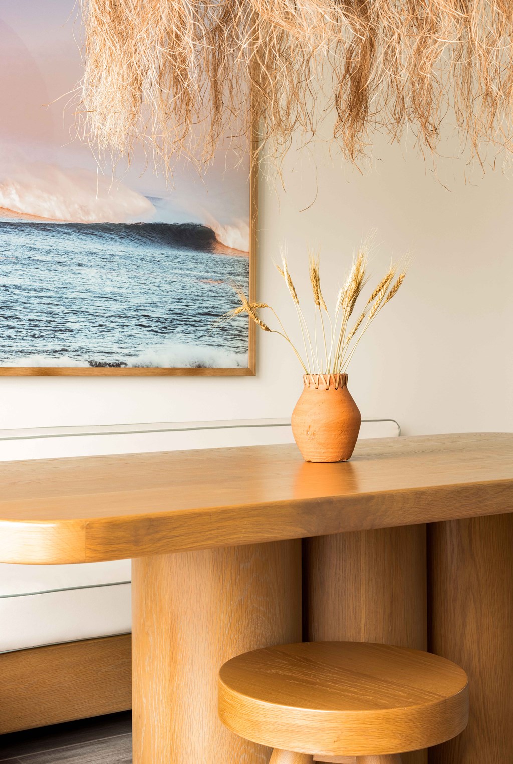A vase with dried plants sits on a wooden table.