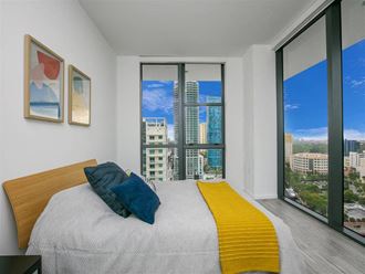 a bedroom with a large window and a bed with a yellow blanket