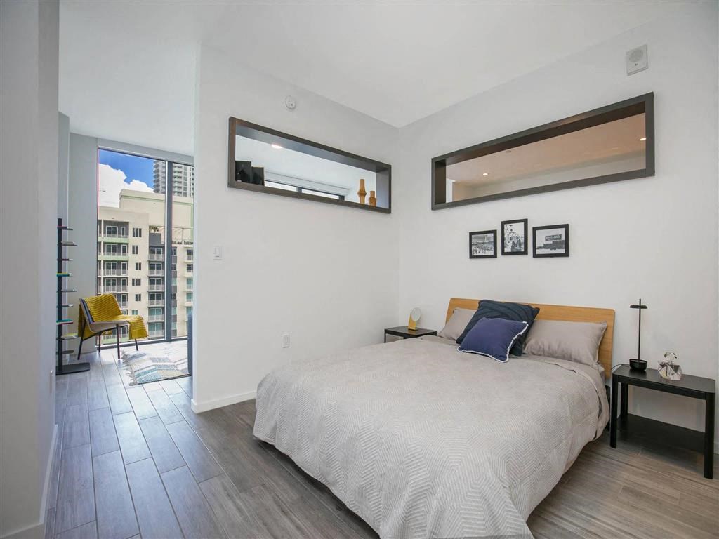 a bedroom with a bed and a sliding glass door to a balcony