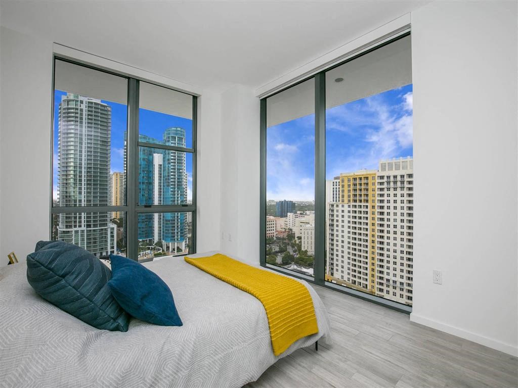 a bedroom with a large window and a bed with pillows