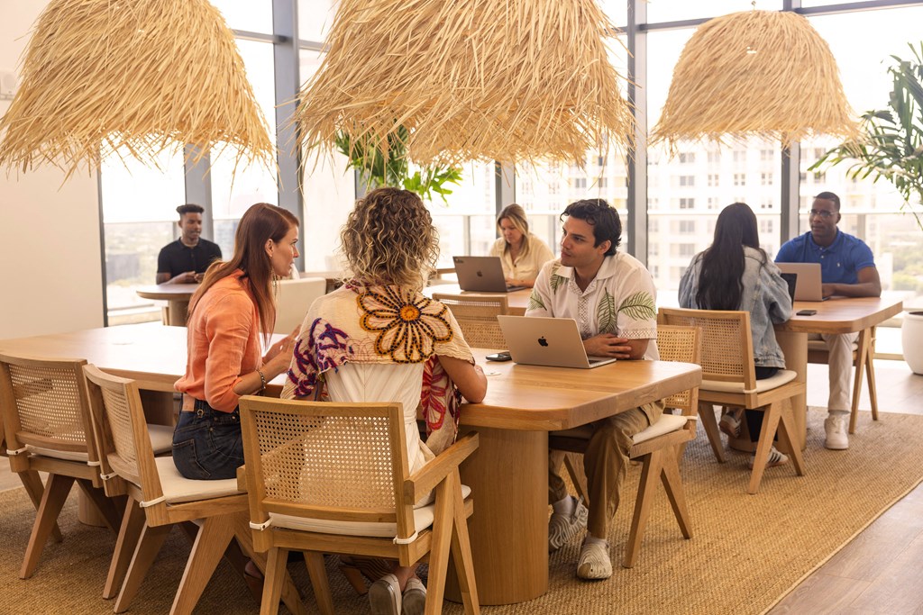 a group of people sitting at a table with laptops