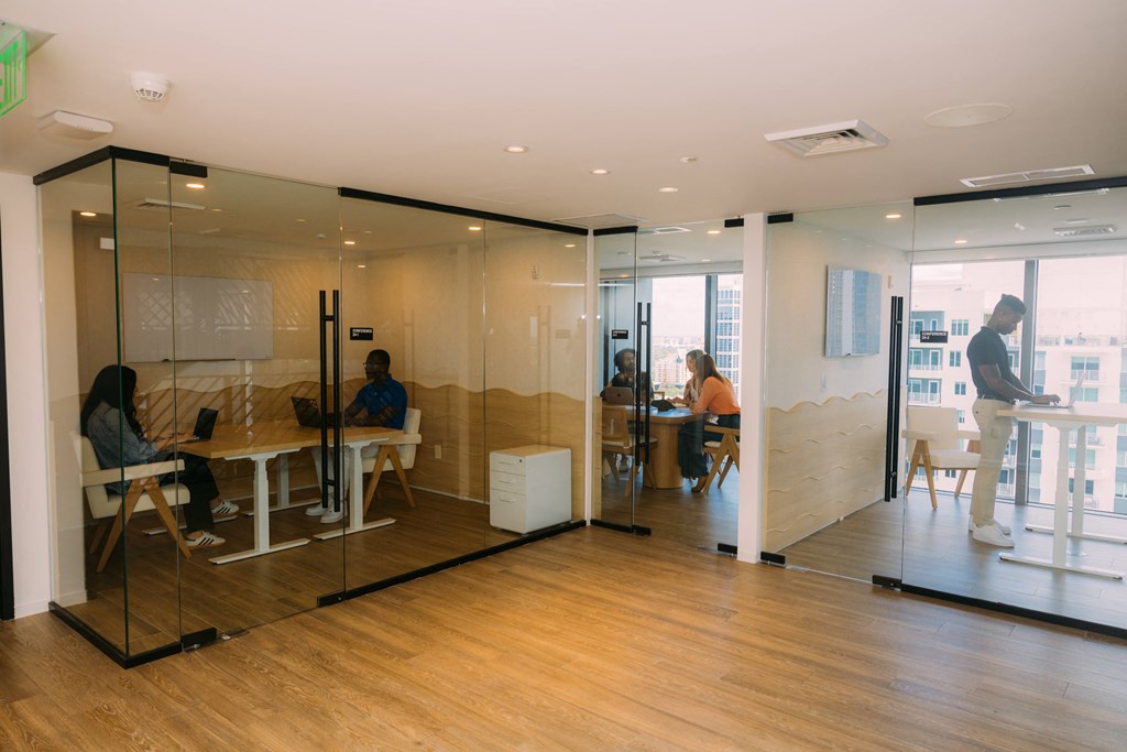 people working in an office with glass walls and a wooden floor