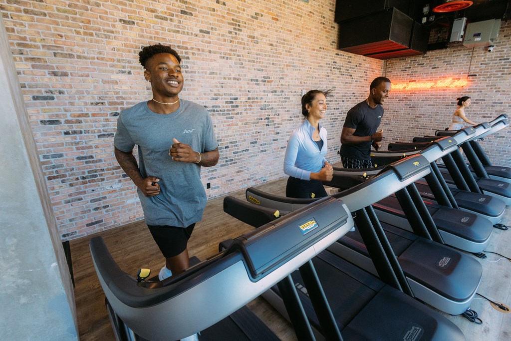 a group of people running on a treadmill in a gym