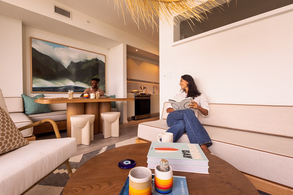 a woman sitting on a couch reading a book in a hotel room
