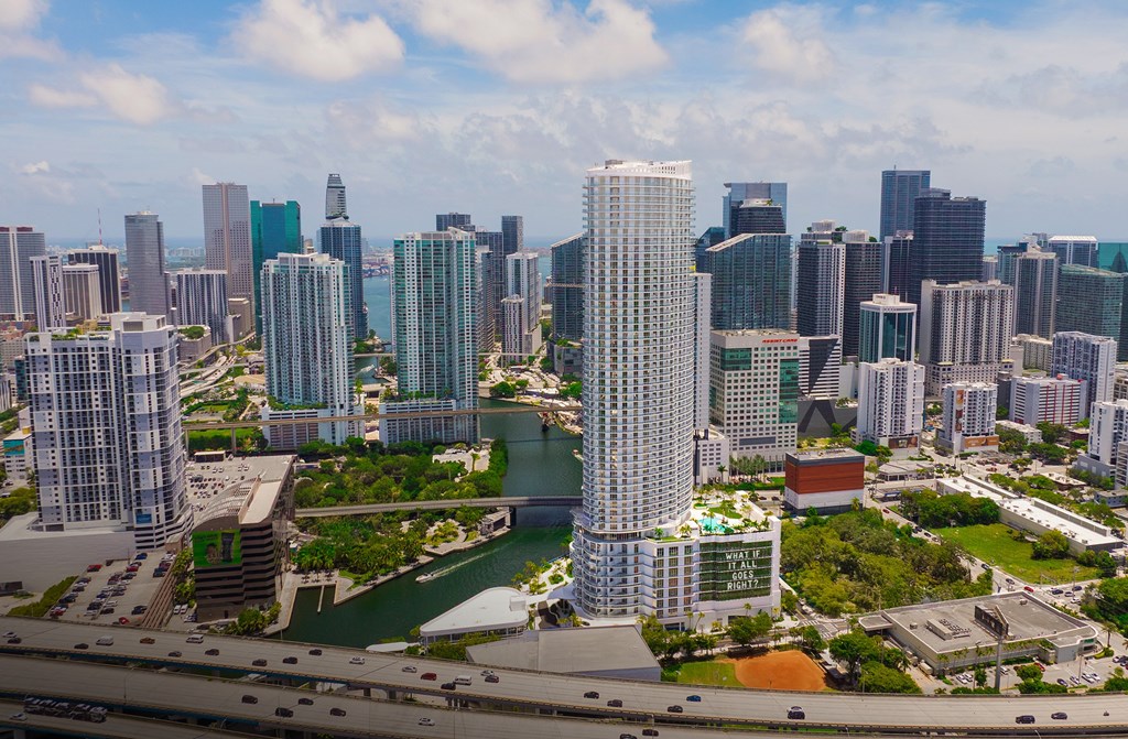 A cityscape with a mix of modern and older buildings, a river running through the city, and a clear sky.