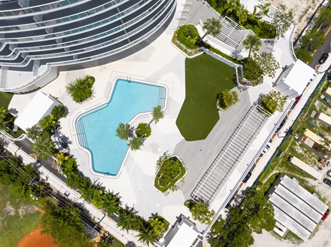 A swimming pool surrounded by a grassy area and trees.