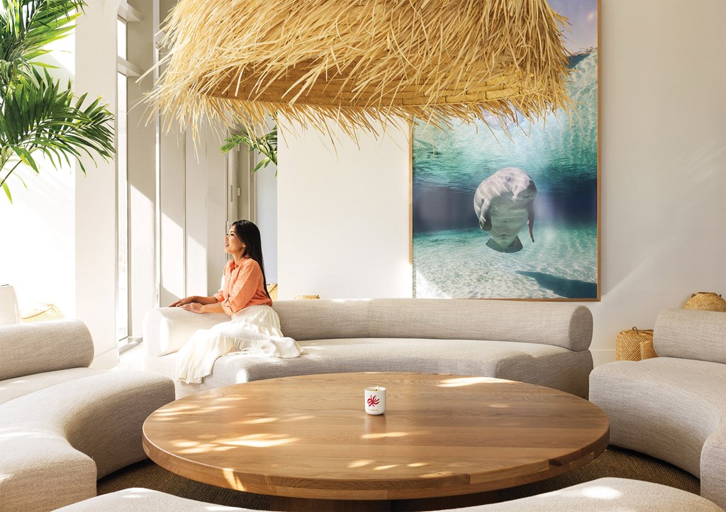 a woman sitting on a couch in a living room with an elephant on the wall