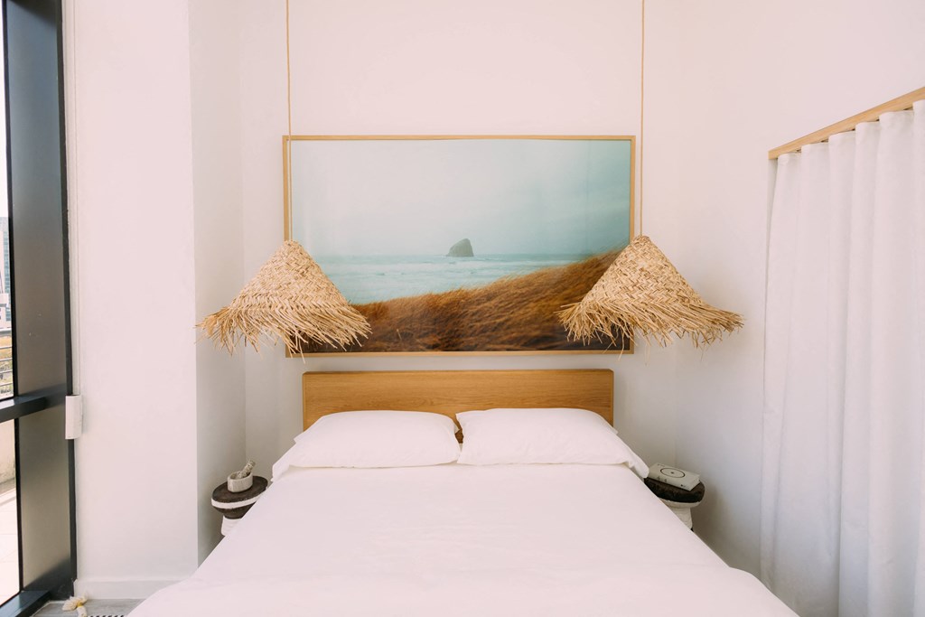 a bedroom with a white bed and a picture of the ocean