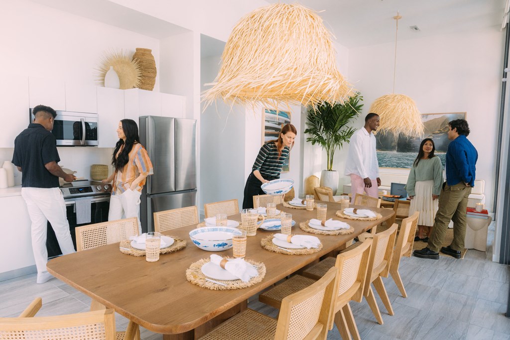 a group of people standing around a dining table in a house