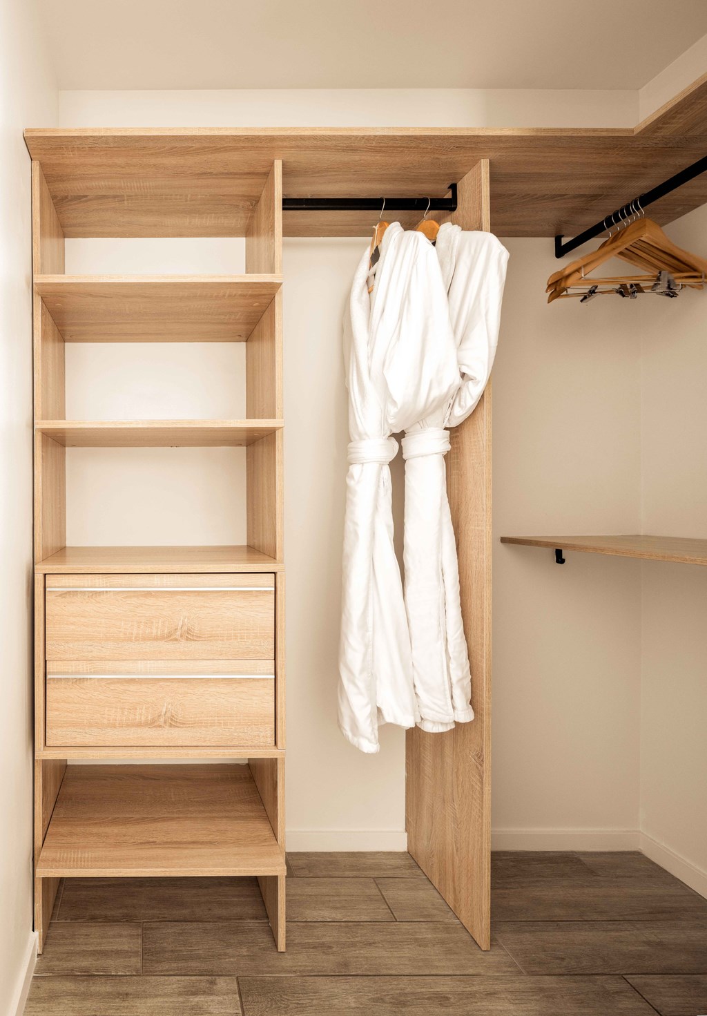 A wooden wardrobe with a white robe hanging on it.